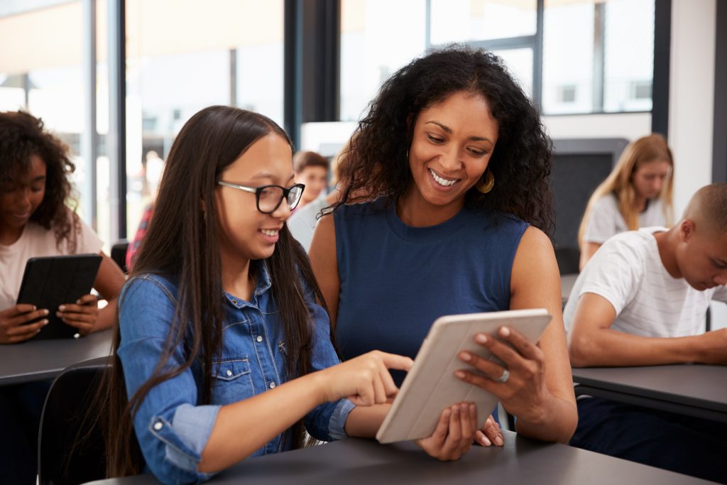 Teacher,Helping,Teenage,Schoolgirl,With,Tablet,Computer
